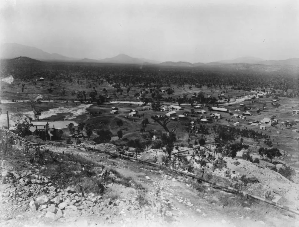 A black-and-white view over a mining township and bare hills