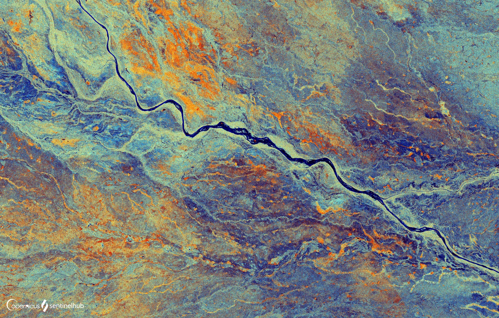 A false-colour satellite radar image with a dark winding river crossing a mottled plain